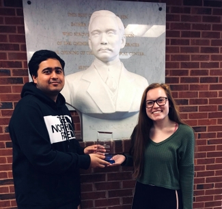 photo of two people with award and bust statue