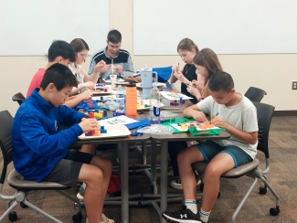 photo of 7 people at a table assembling materials