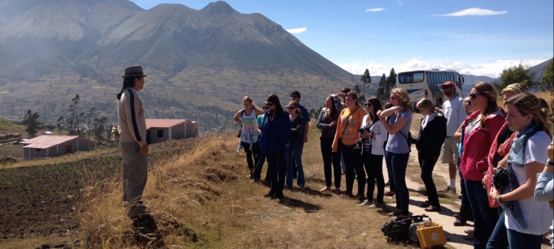 photo. of students with instructor, mountains and village in background