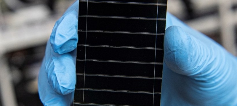 photo of tiny solar cell, held by blue-gloved hand