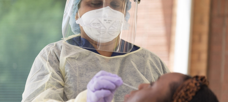 photo of masked nurse administering nasal swab test to patient