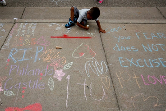 little boy drawing on a sidewalk