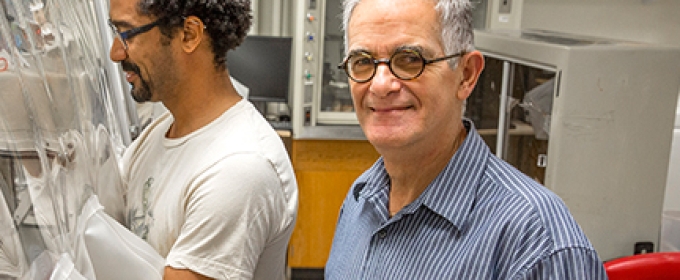 two men in a lab, one looking at camera