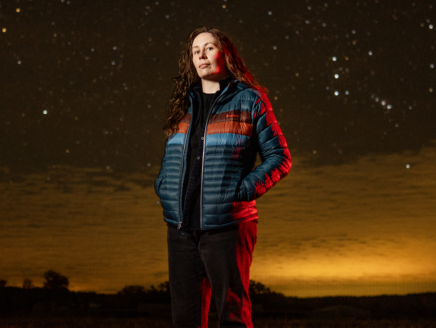 Cassandra Hall standing in a field with vivid sky behind her.