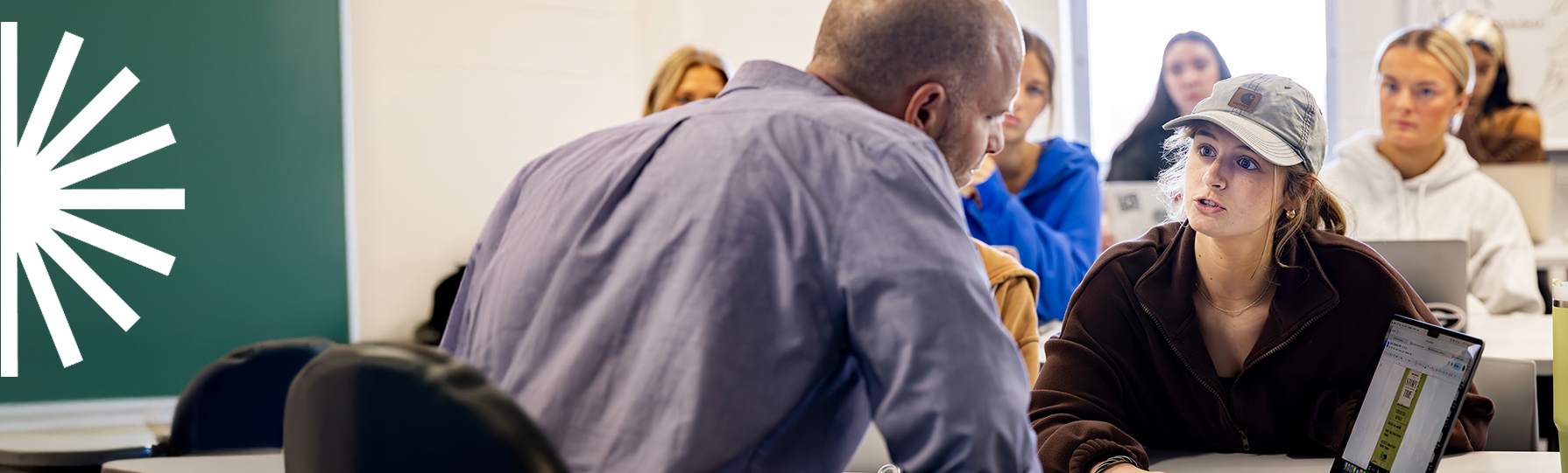 Student talking with professor while other students look on