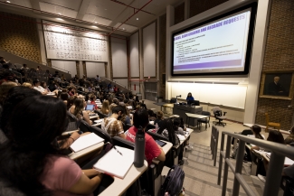 photo of lecture hall with students, screens