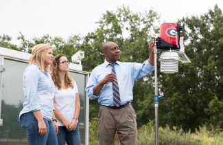 photo of man with students outdoors with rain gauge