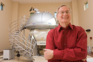 Photo of man standing in front of NMR machine