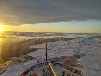 photo of sunrise over frozen sea, with bow of ship