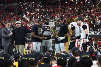 photo of football players on stage, with confetti and trophy