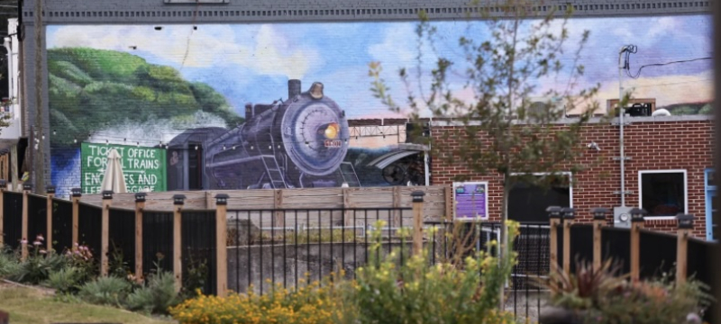 Photo of mural with train on side of downtown building.