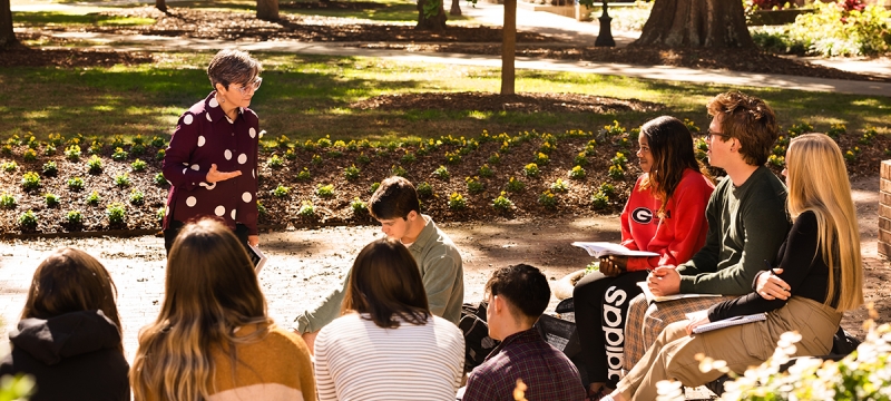 photo of professor and group of students outdoors, day