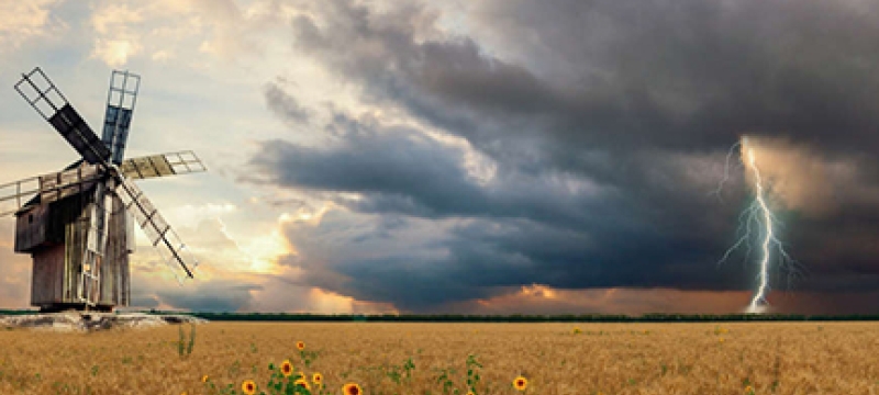 field with windmill and approaching storm