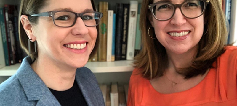 photo of two women in front of bookshelf