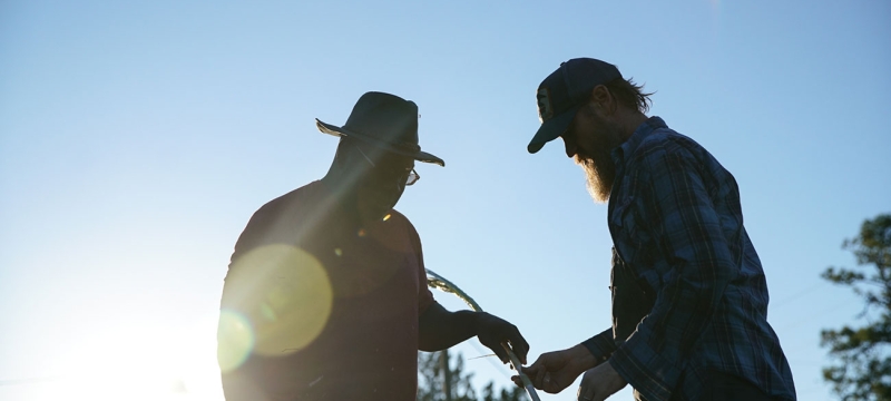 photo of two men, with stalk, sun, and sky