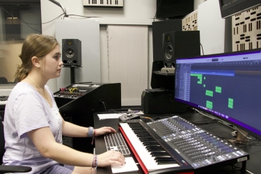 photo of student sitting at sound board with computer screen