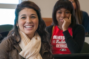Three diverse female students grin as they listen to Daleah Goodwin's lecture in a women's studies class in the Miller Learning Center 
