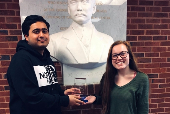 photo of two people with award and bust statue