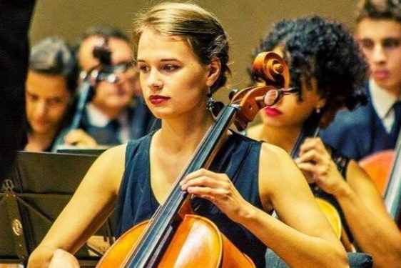 photo of woman playing cello, with other performers in background
