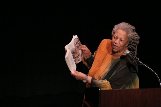 photo of woman reading aloud at a podium with mic