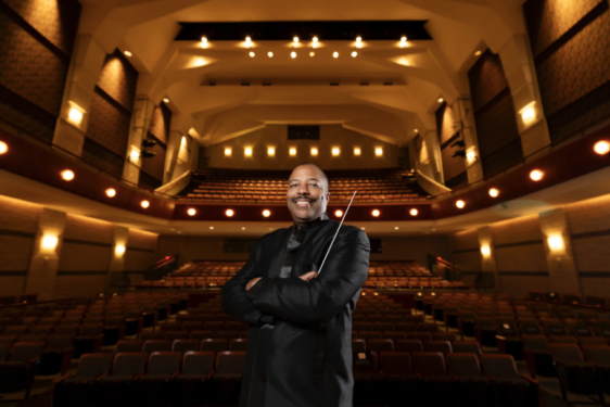 photo of man in performance hall, seats and lights in background