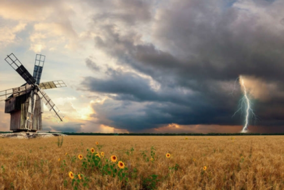 field with windmill and approaching storm