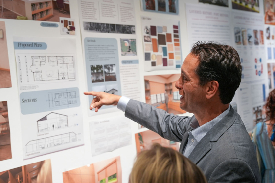 photo of man pointing at posters with drawings and schematics