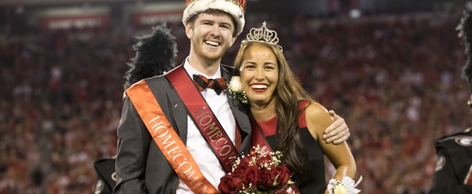 photo of couple with crowns at football stadium, night, blurred crowd background
