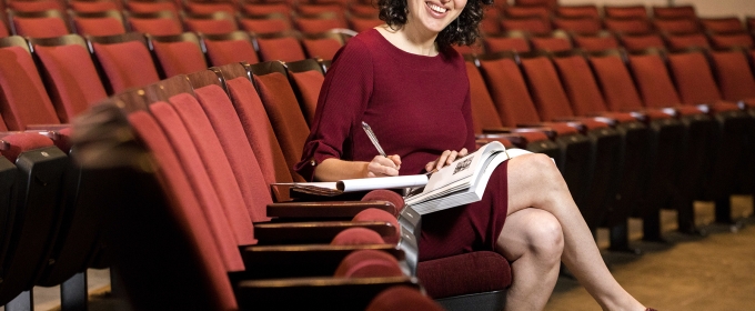 photo of woman seated in auditorium, writing