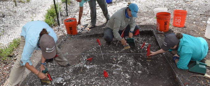 photo of four people on archeological dig, with trowels, brushes and buckets