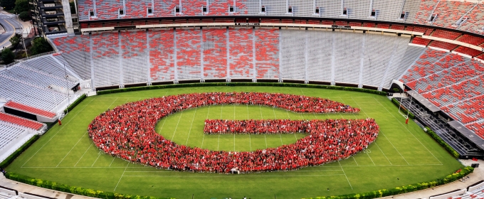 photo of large group of people forming G in stadium