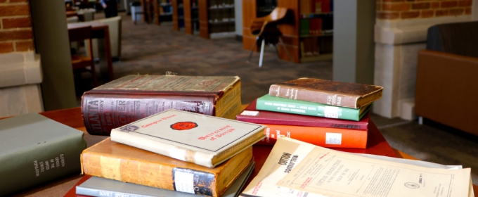 photo of books stacked on a table in a library 