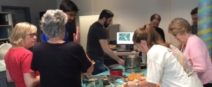 photo of people making plates of food around a table