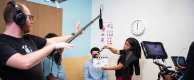 photo of film shoot, with clapper board, people, microphone on boom stand