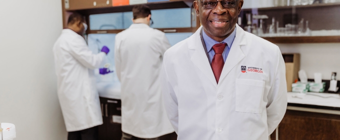 photo of man in lab coat, with two other men in background lab