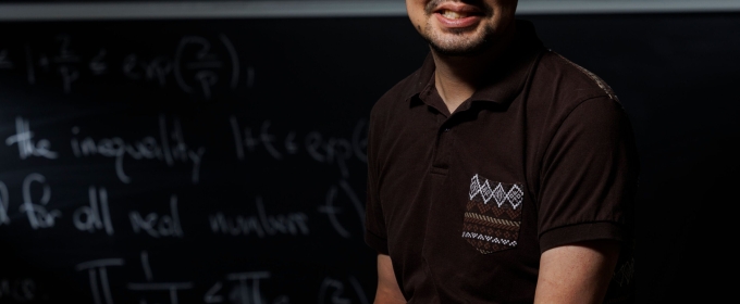 photo of man, chalkboard with letters and numerals in background