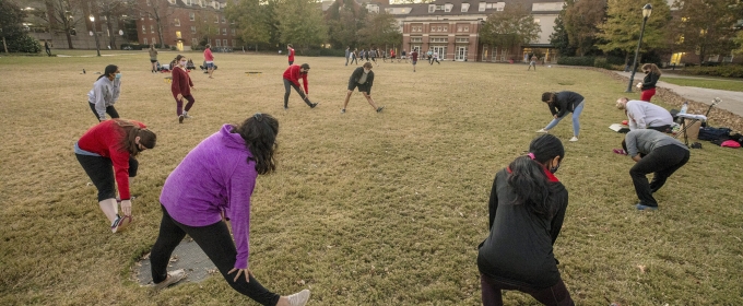 photo of a group of people, in a circle stretching 